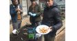 Gardeners taking a break, one holding a plate of potatoes.